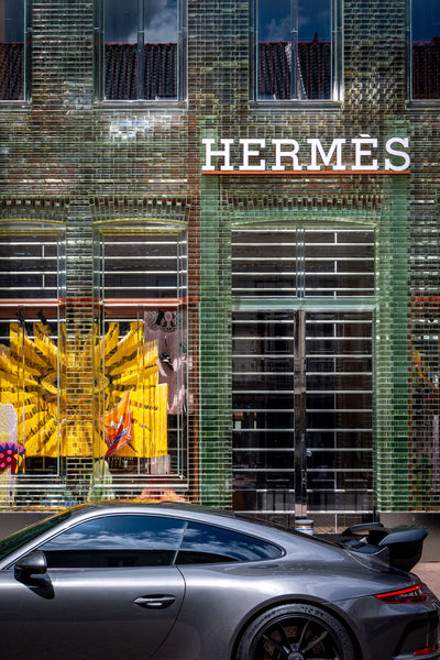 Green Hermès store with grey Porsche in front