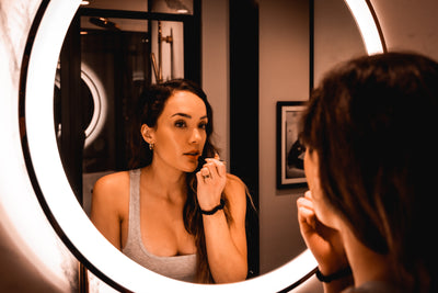 Girl putting on lipstick in mirror